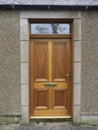 A new wooden Front Door with Brass Fittings set into an Old railway Cottage in the Village of Colliston. Royalty Free Stock Photo