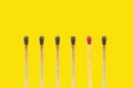 New wooden match stick standing out from many burnt matches stick on yellow background.