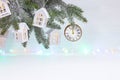 New year background with christmas tree branch, decorative wooden houses, watches, and glowing light garland