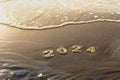 New year 2024 background. 2024 numbers on golden sand of beach in sun rays light and rolling sea wave. holiday, travel Royalty Free Stock Photo