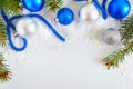 New Year banner with blue and silver Christmas balls in snow, spruce green branches on white background. Xmas decoration.