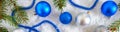 New Year banner with blue and silver Christmas balls in snow, spruce green branches on white background. Xmas decoration. Royalty Free Stock Photo