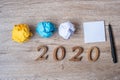 2020 NEW YEAR WITH blank yellow note and crumbled paper on wooden table background. NEW START, Strategy and Goal concept
