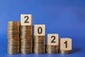 2021 New Year Business and Money concept. Closeup of wooden number block on stack of gold coins on blue background Royalty Free Stock Photo