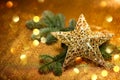 New Year card. Christmas greetings. Golden decorative star with Christmas tree branches, on golden background.