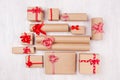 New Year celebration background - different kind craft paper gifts with red ribbons and bows on white wood plank, top view. Royalty Free Stock Photo