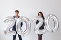 New year, celebration and holidays concept - love couple having fun with sign 2020 made of silver balloons for new year Royalty Free Stock Photo