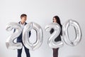 New year, celebration and holidays concept - love couple having fun with sign 2020 made of silver balloons for new year Royalty Free Stock Photo