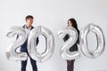 New year, celebration and holidays concept - love couple having fun with sign 2020 made of silver balloons for new year Royalty Free Stock Photo