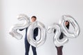 New year, celebration and holidays concept - love couple having fun with sign 2020 made of silver balloons for new year Royalty Free Stock Photo