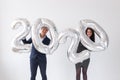 New year, celebration and holidays concept - love couple having fun with sign 2020 made of silver balloons for new year Royalty Free Stock Photo