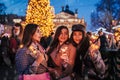 New Year celebration. Women friends burning sparklers in Lviv by Christmas tree on street fair after shopping Royalty Free Stock Photo