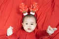 New year and Christmas concept.Headshot of 5 months old cute newborn baby boy wearing christmas antlers of a deer on a red blanket Royalty Free Stock Photo