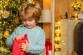 New year Christmas concept. Kid having fun near Christmas tree indoors. Happy child holding a red gift box with both Royalty Free Stock Photo