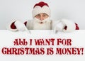 Santa Claus points his fingers at the board with the text - ALL I WANT FOR CHRISTMAS IS MONEY Royalty Free Stock Photo