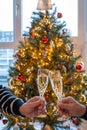 New year or christmas dinner, two man hands with glasses of champagne cava or prosecco wine crystal glasses with christmas tree