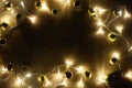 New year christmas frame from golden shiny and matte balls, christmas lights garland on light wood background copy space