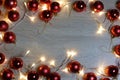 New year christmas frame from red shiny and matte balls, christmas lights garland on light wood background copy space Royalty Free Stock Photo