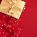 New Year Christmas golden presents with ribbon, Christmas balls, gold confetti stars on red background top view. Flat Royalty Free Stock Photo