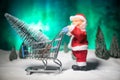 New year or Christmas holiday shopping concept. Store promotions. Santa Claus carrying trolley cart on snow Royalty Free Stock Photo