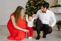 New year and Christmas. Mom and dad hold hands with their little son in the background of the Christmas tree Royalty Free Stock Photo