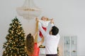 New year and Christmas. Mom and dad hold hands with their little son in the background of the Christmas tree and lift him up Royalty Free Stock Photo