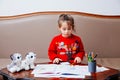 New year christmas pensil little girl writes letter Santa red jacket toy pen kid table sofa Royalty Free Stock Photo