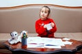 New year christmas pensil little girl writes letter Santa red jacket toy pen kid table sofa Royalty Free Stock Photo