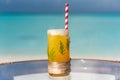 New year and christmas theme cocktail with straw and pine leaves on the glass on the beach Royalty Free Stock Photo