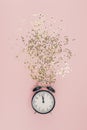 New Year Christmas Top view flat lay black alarm clock twelve covered golden stars confetti copy space millennial pink color paper