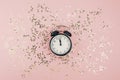 New Year Christmas Top view flat lay black alarm clock twelve covered golden stars confetti copy space millennial pink color paper