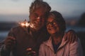 New year. close up of seniors celebrating the new year together at the beach with sparklers lights Royalty Free Stock Photo