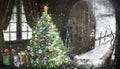 New Year comes into the house. Open brown wooden door irh snow A decorated Christmas tree stands in the background in the room. Royalty Free Stock Photo