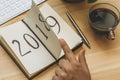 New Year 2019 is coming concept. Female hand flips notepad sheet on wooden table. 2018 is turning, 2019 is opening Royalty Free Stock Photo