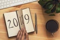 New Year 2019 is coming concept. Female hand flips notepad sheet on wooden table. 2018 is turning, 2019 is opening Royalty Free Stock Photo