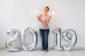 New 2019 Year is coming concept - Happy woman standing near silver colored numbers and sparklers indoors. Royalty Free Stock Photo