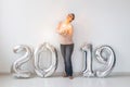 New 2019 Year is coming concept - Happy woman standing near silver colored numbers and sparklers indoors. Royalty Free Stock Photo