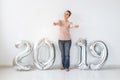 New 2019 Year is coming concept - Happy woman standing near silver colored numbers and sparklers indoors. Royalty Free Stock Photo