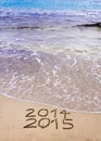 New Year 2015 is coming concept - inscription 2014 and 2015 on a beach sand, the wave is covering 2014 Royalty Free Stock Photo