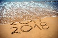 New Year 2018 is coming concept - inscription 2017 and 2018 on a beach sand, the wave is covering digits 2017. New Year 2018 celeb Royalty Free Stock Photo