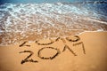 New Year 2017 is coming concept - inscription 2017 and 2016 on a beach sand, the wave is covering digits 2016. New Year 2017 celeb Royalty Free Stock Photo