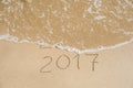 New Year 2017 is coming concept - inscription 2016 and 2017 on a beach sand, the wave is almost covering the digits 2016 Royalty Free Stock Photo