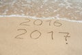 New Year 2017 is coming concept - inscription 2016 and 2017 on a beach sand, the wave is almost covering the digits 2016 Royalty Free Stock Photo