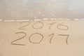 New Year 2017 is coming concept - inscription 2016 and 2017 on a beach sand, the wave is almost covering the digits 2016 Royalty Free Stock Photo