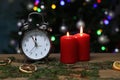 New year composition with an alarm clock and red burning candles, in front of colorful bokeh lights Royalty Free Stock Photo