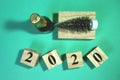 New Year composition with bottle champagne and decorative new year tree. Wooden cube block building the word 2020 Royalty Free Stock Photo
