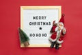 New Year composition of Santa Claus, tree, white felt board with text Merry Christmas, ho ho ho on red background Holiday card Royalty Free Stock Photo