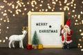New Year composition of white deer, Santa Claus, lights, skier, tree, gift box, felt board with text Merry Christmas on dark woode Royalty Free Stock Photo