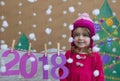 New Year 2018 concept. Beautiful small girl decorating the New Year numeral. background of a painted Christmas tree and