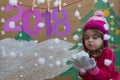 New Year 2018 concept. Beautiful small girl decorating the New Year numeral. background of a painted Christmas tree and